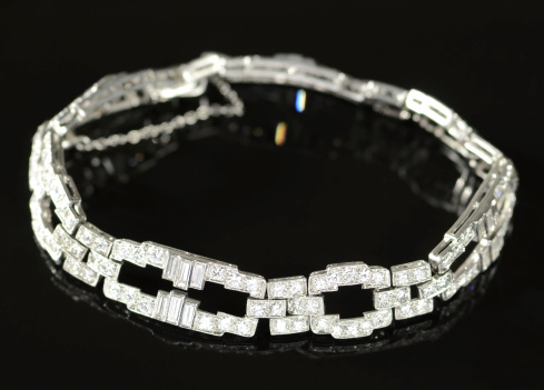 Expensive diamond and platinum Art Deco bracelet with round-cut and baguett-cut diamonds on a black background.