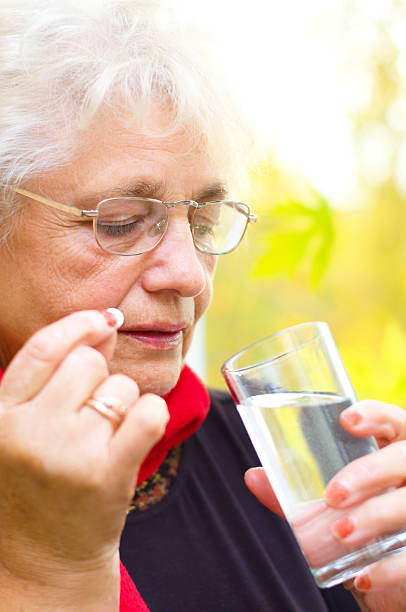 istock old woman holding a pill in her hand 187577073