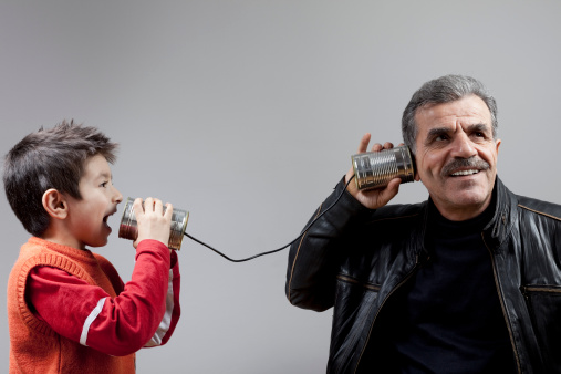 Grandfather talking to grandson on tin can phone