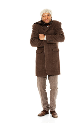 Full length portrait of mature african man in warm clothes feeling cold while standing over white background