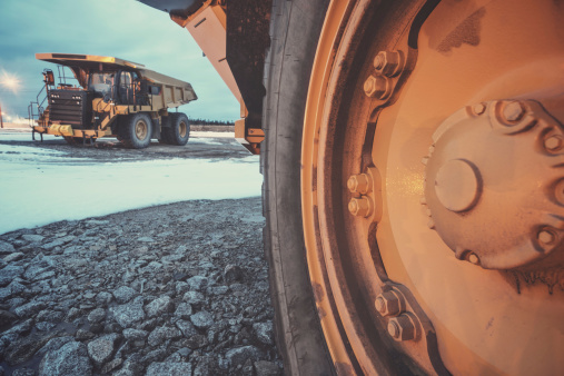 Two massive off-highway dump trucks on a large construction site in Winter.