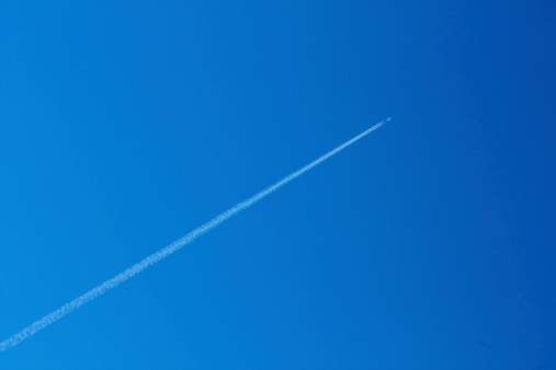 Airplane with contrails against dark blue sky