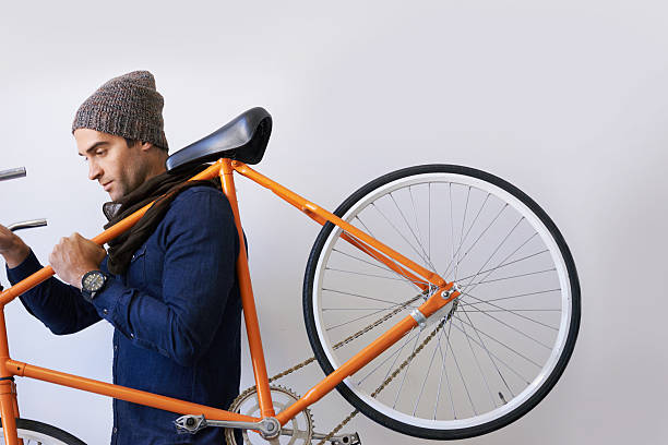 On the move with feet and wheels Shot of a hop young man carrying a retro bike hipster bike stock pictures, royalty-free photos & images