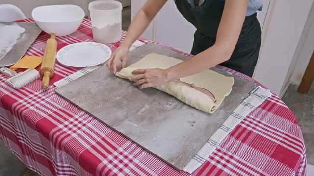 Time lapse view close-up of Hispanic young woman preparing ham bread or 