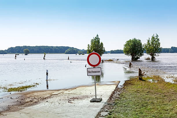 High water warning street sign in germany. Spa town embankment under water. High water warning sign, red and white flood barrier.