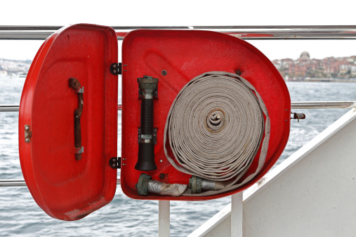 An outdoor fire hose cabinet at a ferry deck with cabinet lid left opened.