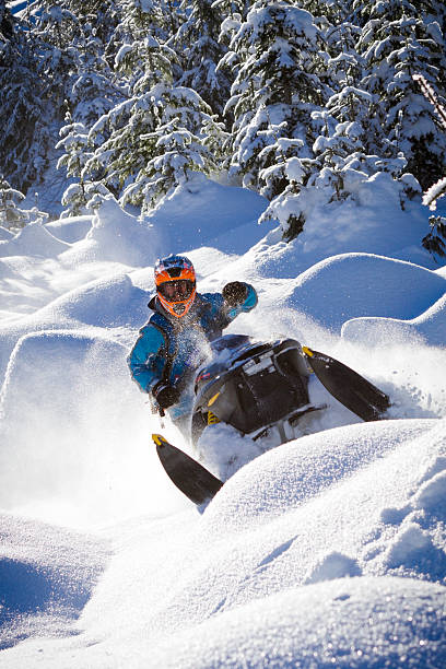 Snowmobiler riding on mounds of snow stock photo