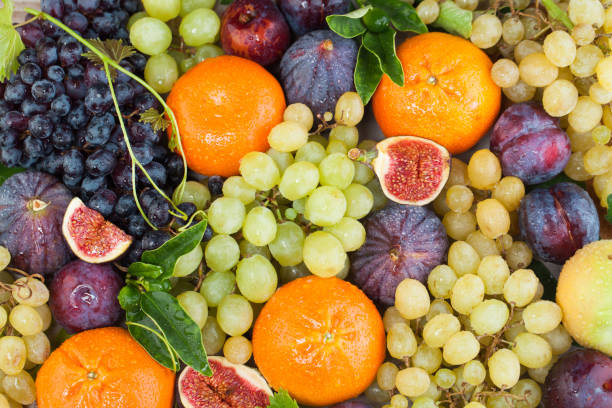istock Bright fruit background, top view. Grape, figs, orange tangerine and plum with green leaves 1875952840
