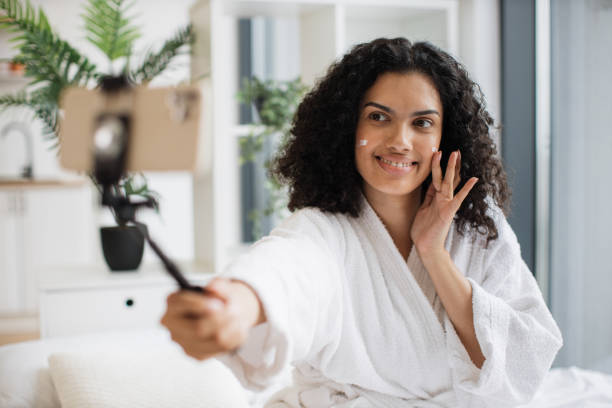 istock Multinational woman vlogger applying cream on cheek 1875961116