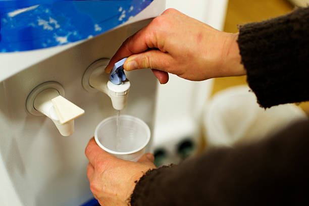 At the water cooler A person filling up a plastic cup with water from a dispenser. water cooler stock pictures, royalty-free photos & images