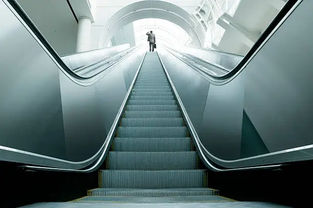 A businessman at the top of an escalator surveying the possibilities.