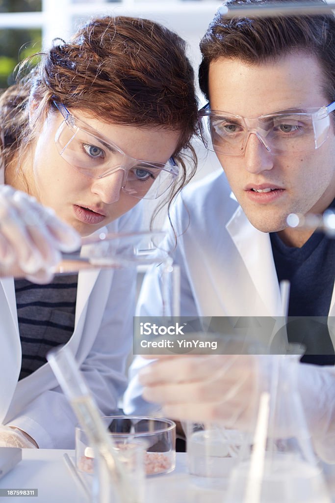 Equipe de pesquisadores vertendo líquido química, trabalhando no laboratório experimentar Vertical - Foto de stock de Laboratório royalty-free
