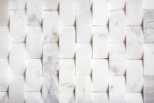 Natural white modern tile used for bathrooms, kitchen backsplash or featured walls. Upward curved or cambered 2x4 tile, flat lay. Selective focus.