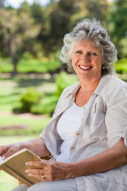 istock Old woman with a book smiling 187608724