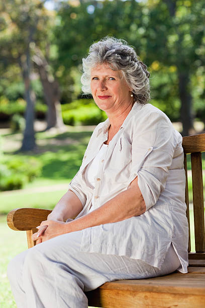 istock Old woman sitting down outdoors smiling 187608792