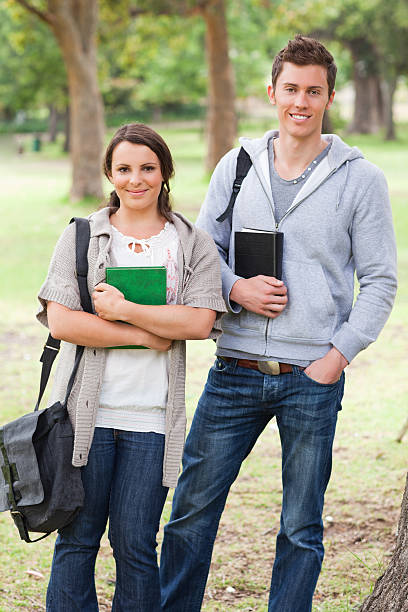 istock Happy students holding books in a park 187610724