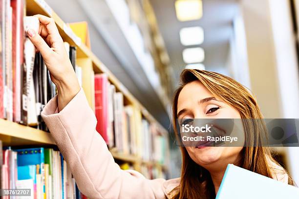 Loira Feliz Navegação As Estantes À Procura De Algo Para Ler - Fotografias de stock e mais imagens de 20-29 Anos