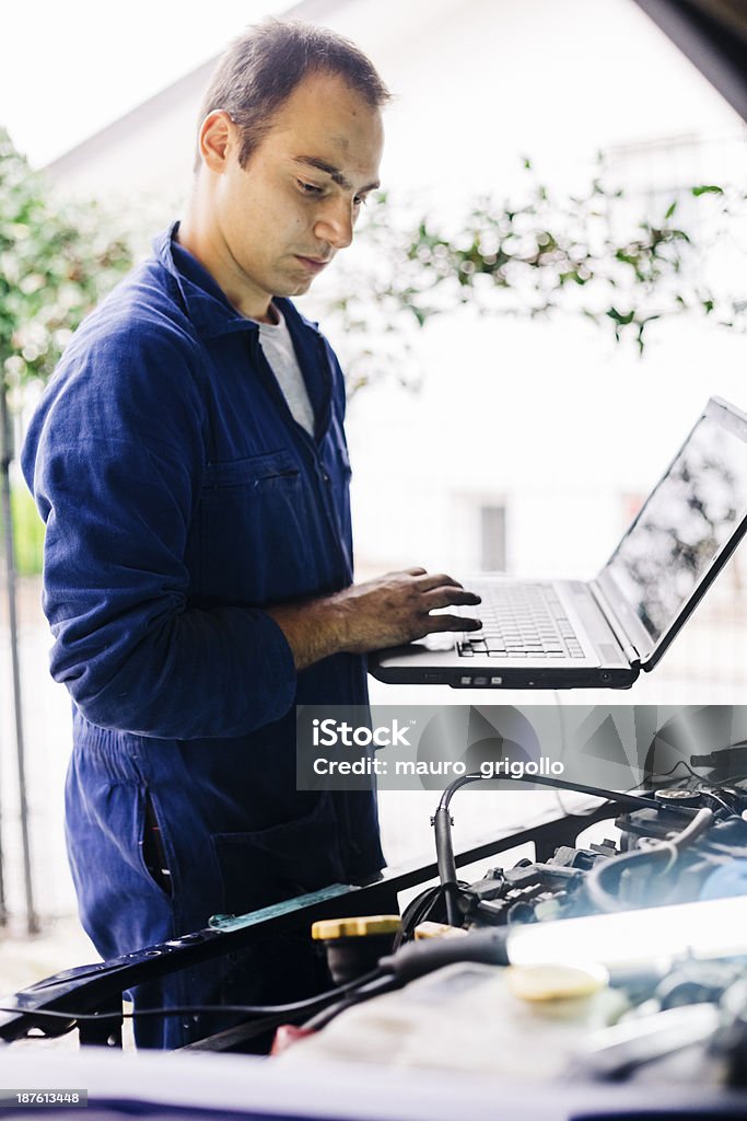 Mécanicien en utilisant l'ordinateur portable tout en travaillant sur la voiture - Photo de Adulte libre de droits