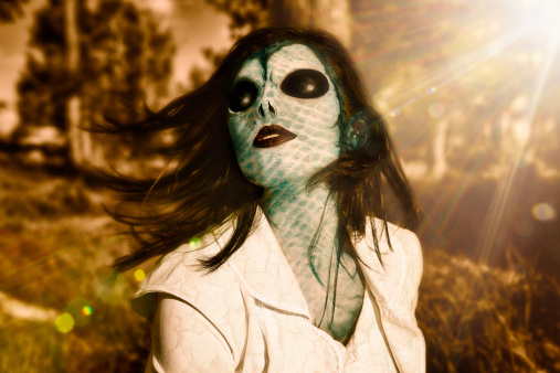 Beautiful Alien woman.  Snake like woman soaking up the sun's rays just like a  common reptile.  Sun Haze and Sun flare.Outdoors In the woods.