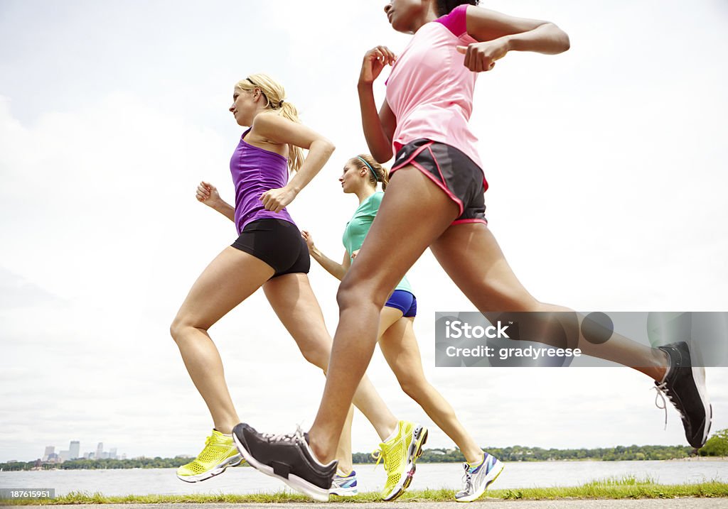 Ladies keeping fit Cropped side view of a group of athletes jogging beside a lake 20-29 Years Stock Photo