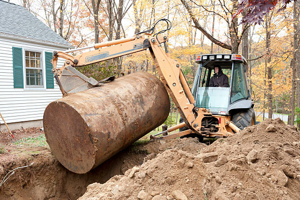 Man removing old oil tank with excavator A man sitting in an excavator removes an old, rusty underground oil tank from a residential yard. fuel storage tank photos stock pictures, royalty-free photos & images