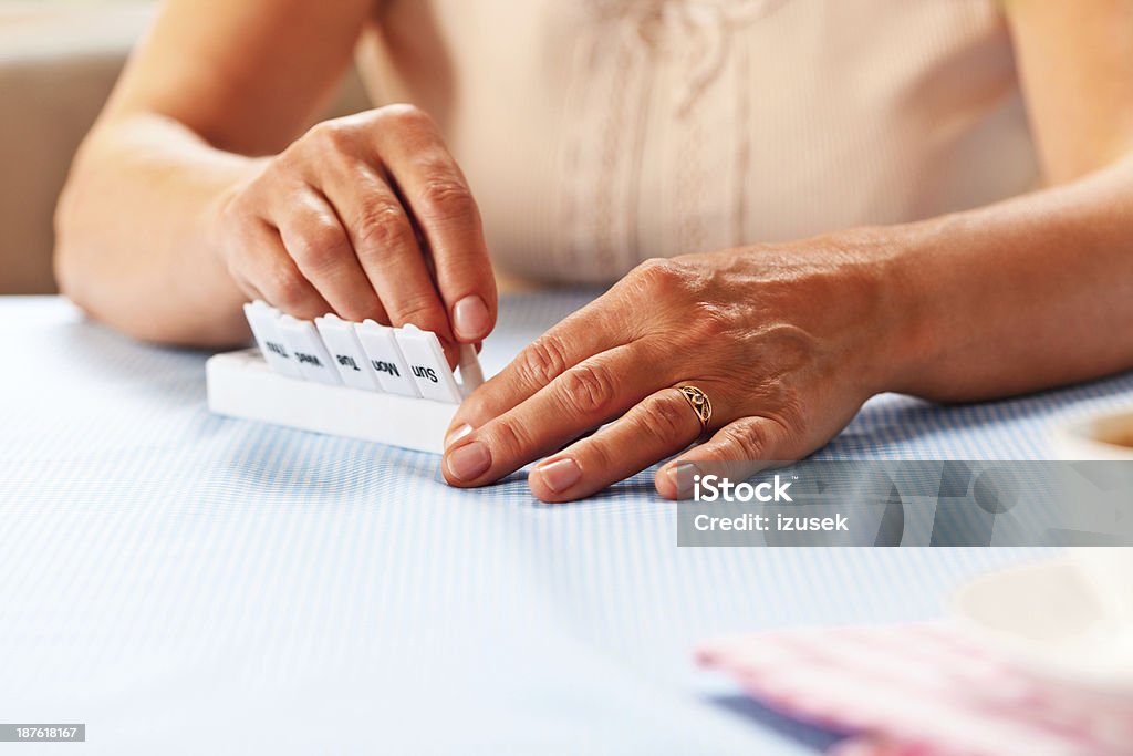 Pill organizer Close up of elderly hands placing pills into a pill box. Medicine Stock Photo
