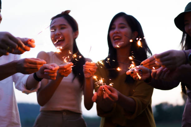 istock Group of Asian people playing sparkling firework. 1876189734