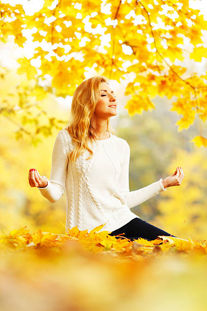 istock Woman meditating in autumn park 187620055