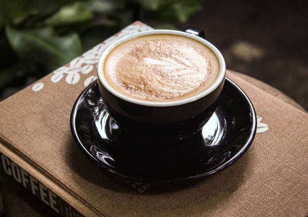 istock Latte art coffee in black coffee cup on wooden table. 1876227456