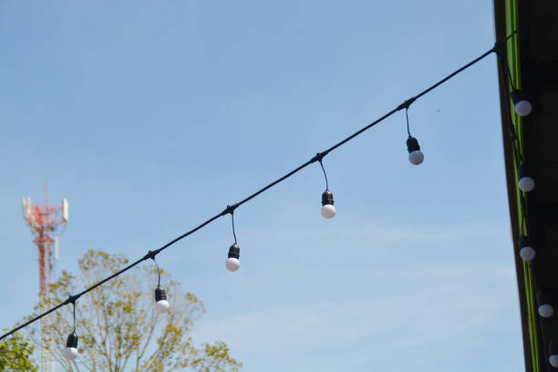 istock Light bulbs hang on electric wire and sky background. 1876243818