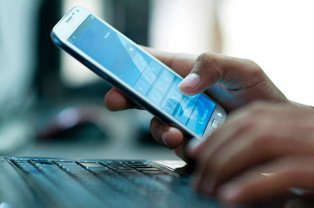 Businessman hand using laptop and mobile phone in office