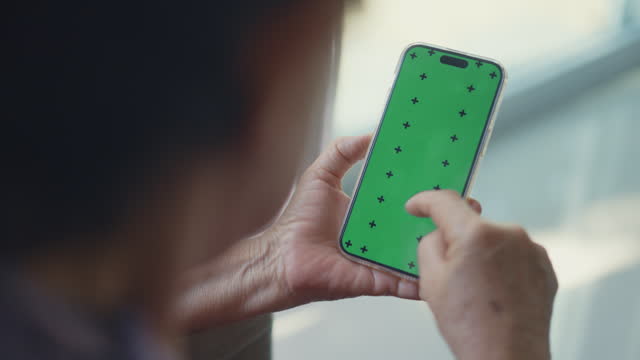 Mature women using chroma key green screen smartphone at home.