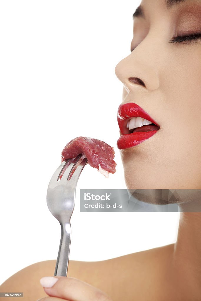 Young beautiful woman eating raw meat. Young beautiful woman eating raw meat. Isolated on white Adult Stock Photo