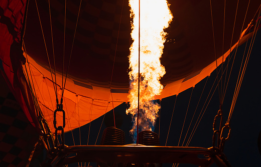 Hot air balloon is inflating before liftoff - Hatshepsut Temple at sunrise in Valley of the Kings and red cliffs western bank of Nile river- Luxor- Egypt