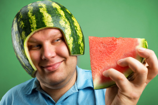 Bizarre man in a helmet from watermelon preparing to eat
