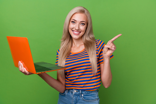 Photo of satisfied lovely girl wear stylish striped clothes recommend it programming courses isolated on green color background.