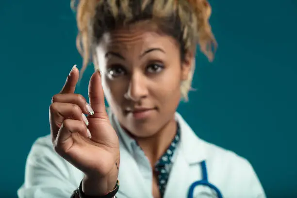 healthcare professional gestures a small amount with her fingers, perhaps indicating a precise dosage or a minor concern