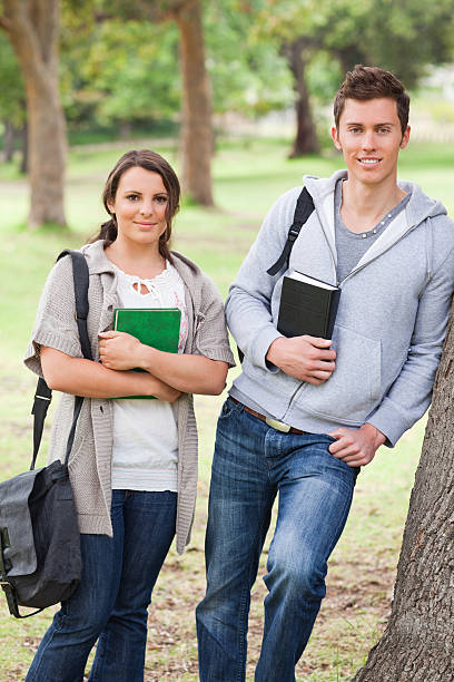 istock Smiling students holding books in a park 187647532