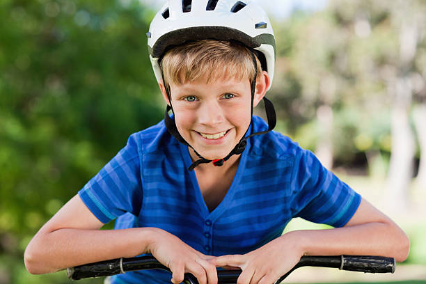 istock Happy boy wearing helmet is leaning on his bicycle handlebars 187647717