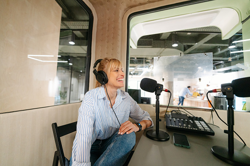 Photo of a young woman, a podcast hosts, recording an interesting content for her  podcast
