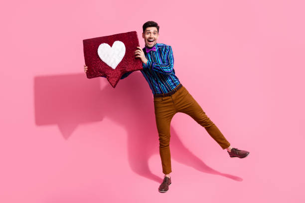 foto de cuerpo entero de un joven que demuestra su símbolo de corazón hecho a mano para la novia sorprendiéndola aislada sobre fondo de color rosa - double click fotos fotografías e imágenes de stock