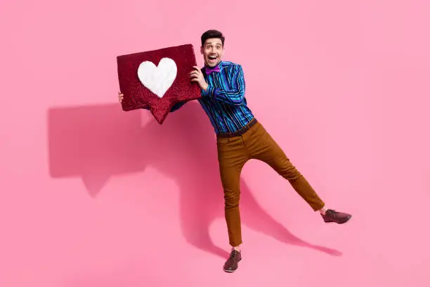 Photo of Full body length photo of young guy demonstrate his handmade heart symbol for girlfriend surprising her isolated on pink color background