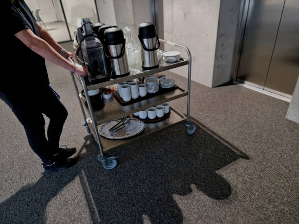 the serving cart delivers refreshments to the office coffee and tableware must not be missing at any corporate meeting. stainless steel lift, the door is driven by a hotel waitress