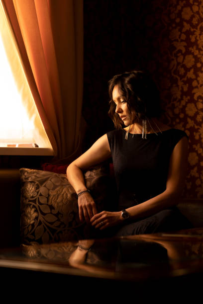 istock A young beautiful brunette with a bracelet and a watch on her hands is thinking while sitting in an armchair 1876587868