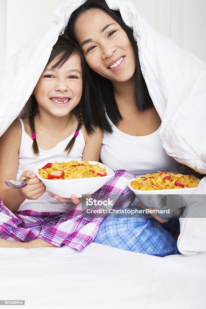 Madre e figlia tenendo la prima colazione a letto - Foto stock royalty-free di 30-34 anni