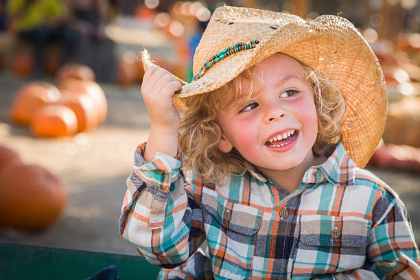 felice ragazzino in cappello da cowboy alla zucca patch - market farmers market agricultural fair child foto e immagini stock