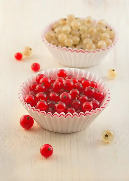 Autumn healthy dessert. Two paper caps with white and redberries of redcurrant and whitecurrant on the old wooden table background. Fall season. Ingredients for sweet jelly.