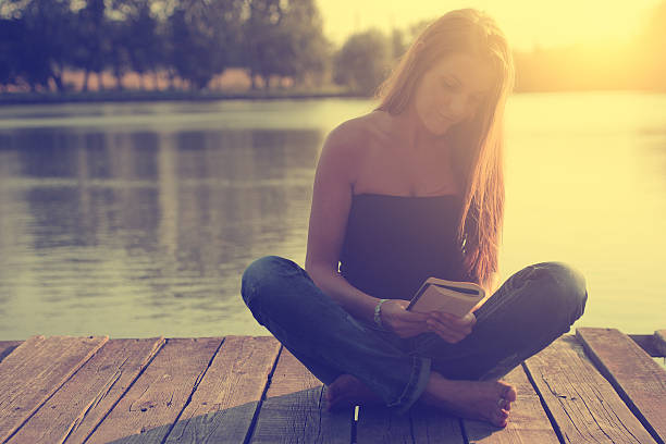 istock A woman sitting on a dock reading at the lake 187665297