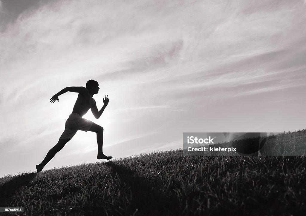Photograph of a man in silhouette running up a hill Silhouette of young man running up a hill. Running Stock Photo