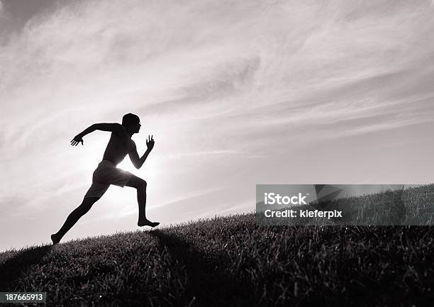 Photograph Of A Man In Silhouette Running Up A Hill Stock Photo - Download Image Now